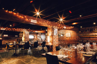 Dining area with string lights and brick walls in a restaurant setting. Fremantle Cellar