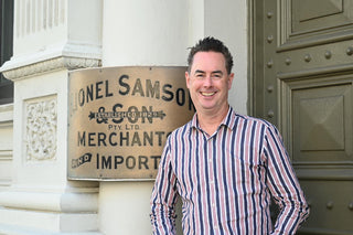 Man standing in front of a building with a sign reading 'J. Lionel Samson & Co'.