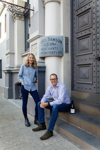 Two people sitting on steps in front of a building with a sign that reads 'H. L. Samson & Co.'