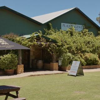 Green building with 'Plantagenet' sign, outdoor seating area with picnic table and plants.