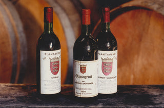 Three bottles of Plantagenet wine in front of wooden barrels