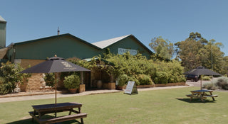Outdoor setting with picnic tables, umbrellas, and a building in the background