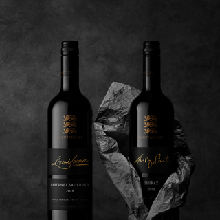 Two wine bottles with labels on a dark background