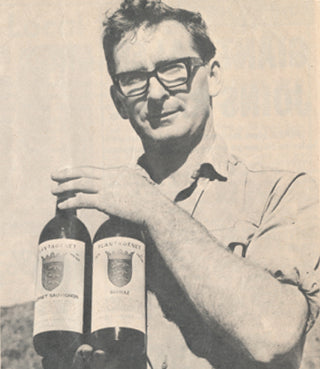 Black and white photo of Tony Smith holding two wine bottles.